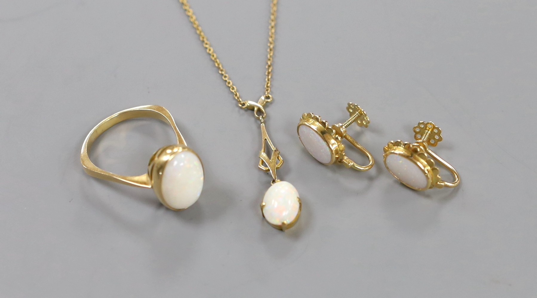 A 750 yellow metal and oval cabochon white opal set ring, size U/V, gross weight 6.2 grams, together with a pair of yellow metal and opal set ear clips and a similar pendant necklace.